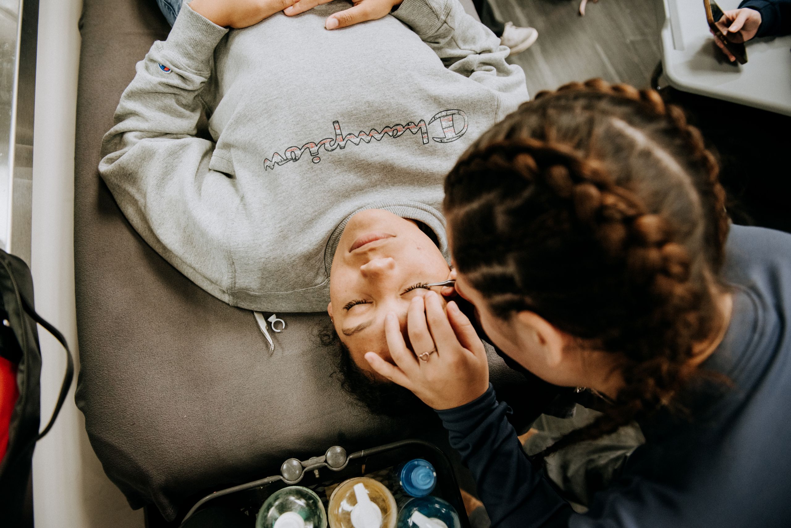 A woman giving another woman eyelash extensions.